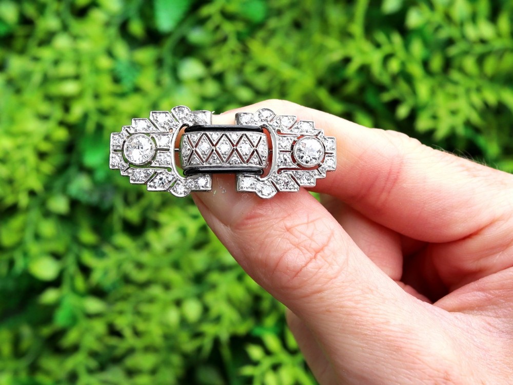 An Art Deco platinum brooch featuring geometric stepped motifs, diamond pave setting, central lattice detail, and black enamel accents. View II