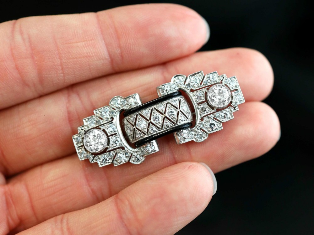 An Art Deco platinum brooch featuring geometric stepped motifs, diamond pave setting, central lattice detail, and black enamel accents. View III