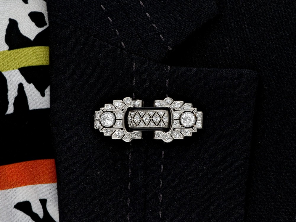 An Art Deco platinum brooch featuring geometric stepped motifs, diamond pave setting, central lattice detail, and black enamel accents. View XII