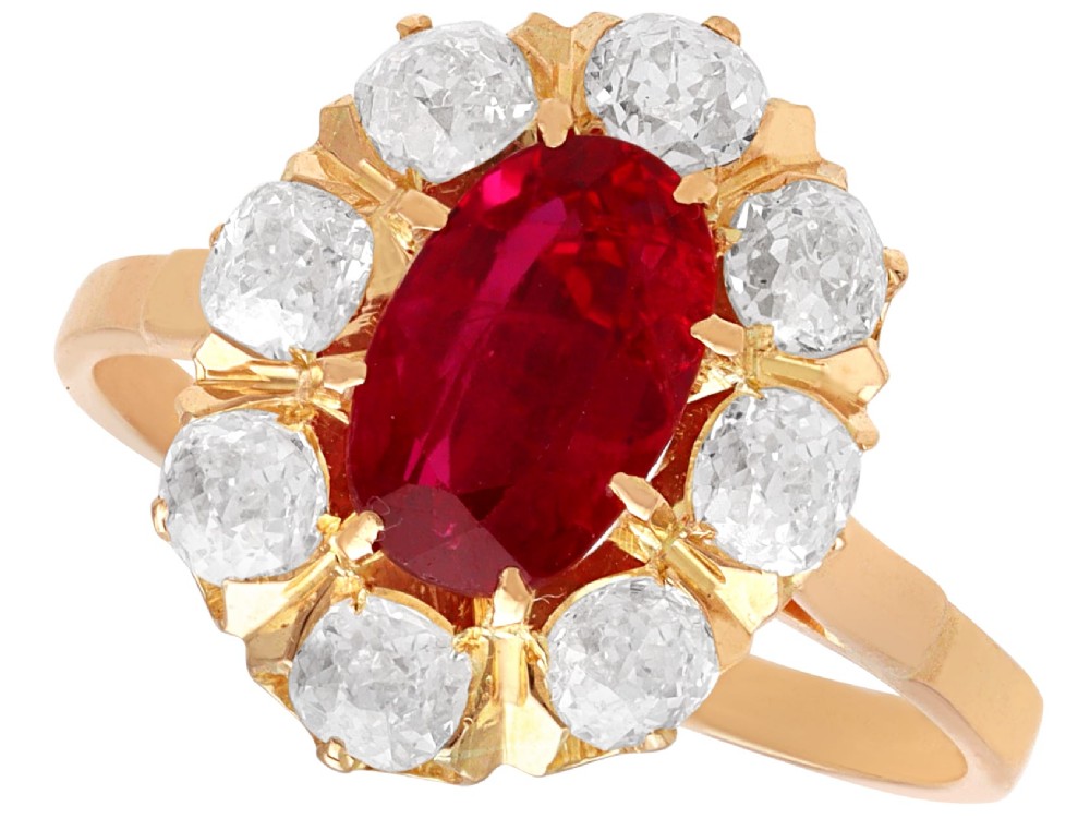 An 18ct rose gold cluster ring featuring a central oval red ruby surrounded by eight old cut diamonds set in individual claw settings.