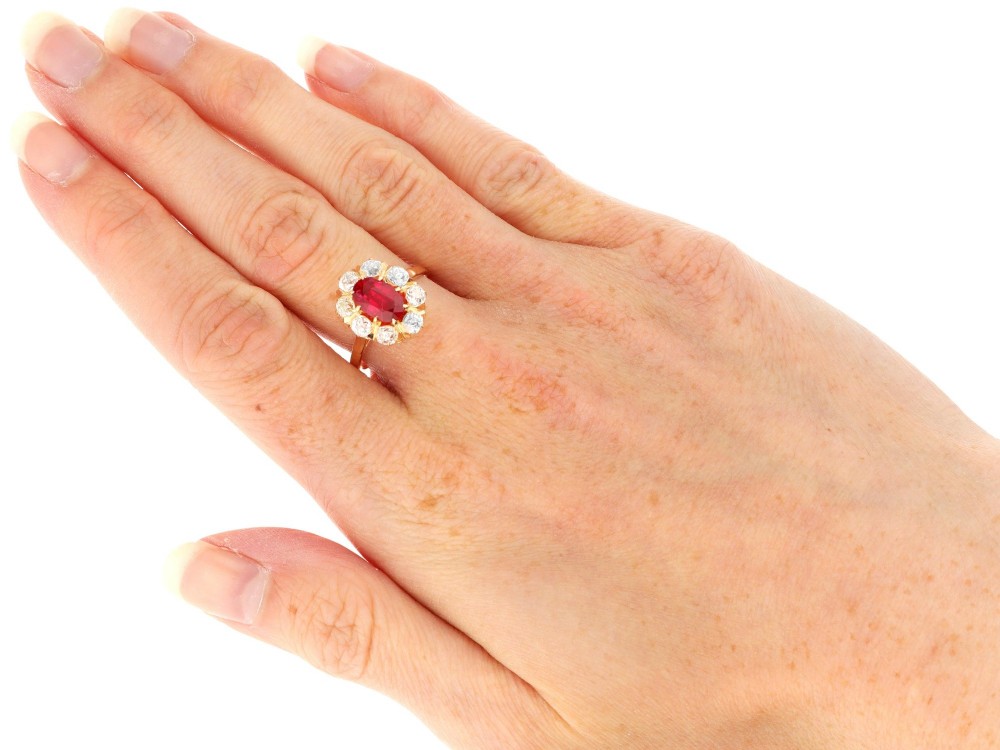An 18ct rose gold cluster ring featuring a central oval red ruby surrounded by eight old cut diamonds set in individual claw settings. View XI