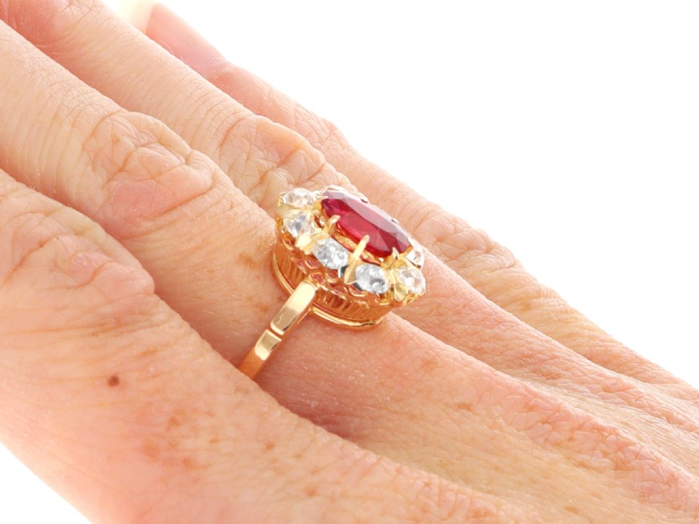 An 18ct rose gold cluster ring featuring a central oval red ruby surrounded by eight old cut diamonds set in individual claw settings. View XII