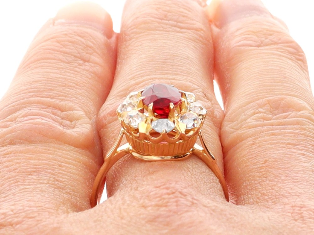 An 18ct rose gold cluster ring featuring a central oval red ruby surrounded by eight old cut diamonds set in individual claw settings. View XIII