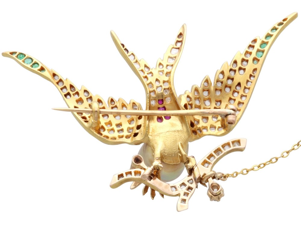 An antique Victorian 18ct yellow gold bird brooch set with diamonds on the wings, emeralds along the outer feathers, a natural pearl body, and ruby details. View VIII