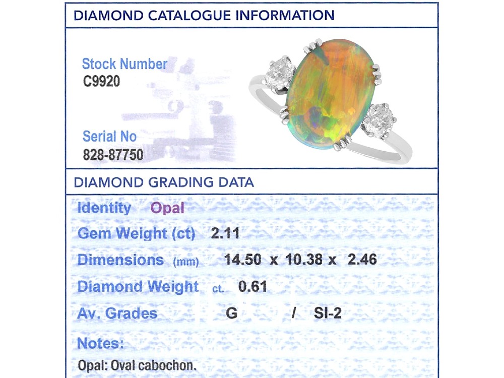 An antique platinum trilogy ring featuring a central oval cabochon opal flanked by two round cut diamonds. View XII