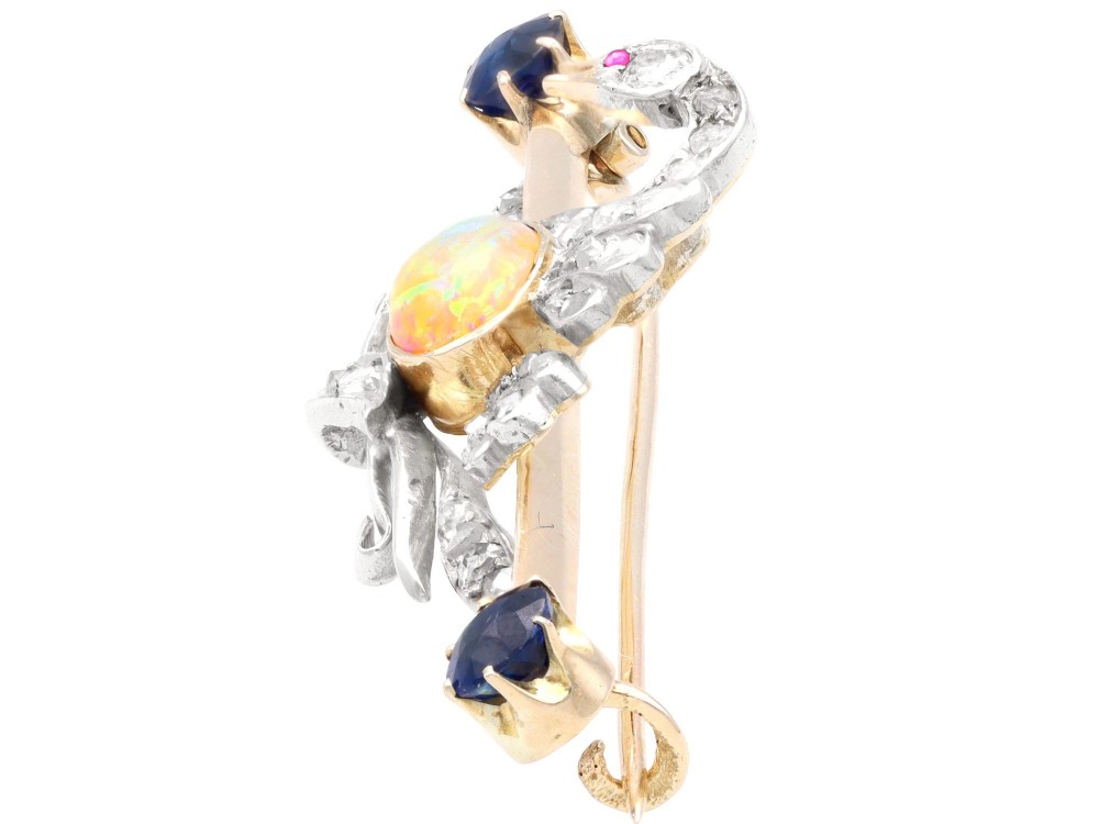 An antique Victorian 9ct gold bar brooch featuring a central swan motif set with diamonds and an oval opal body, flanked by two blue sapphires. View V