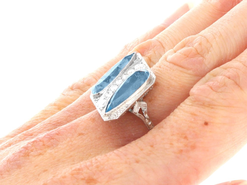 An Art Deco platinum cocktail ring featuring two pear-cut light blue aquamarines set diagonally beside a central row of round diamonds with millegrain borders. View XI