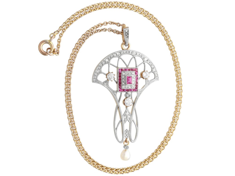 An Edwardian openwork yellow gold pendant set with a central square-cut ruby surrounded by small rubies, diamonds, and a suspended natural pearl drop. View VIII