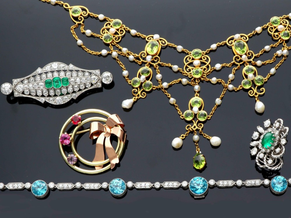 An Art Deco platinum brooch featuring three central step-cut green emeralds surrounded by a geometric lattice of diamonds with millegrain borders. View IV
