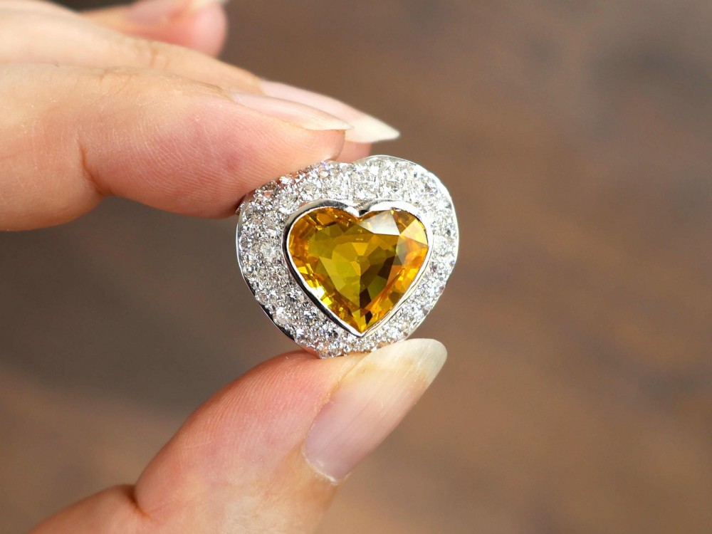 A platinum heart-shaped pendant set with a central faceted yellow sapphire surrounded by a double border of round diamonds. View V
