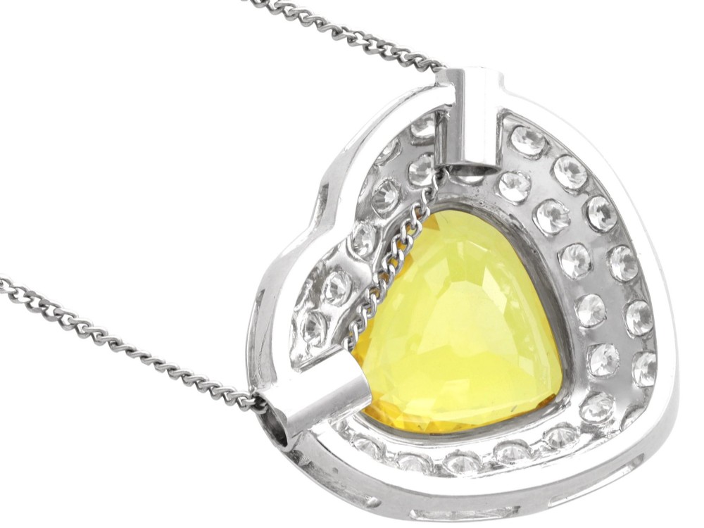 A platinum heart-shaped pendant set with a central faceted yellow sapphire surrounded by a double border of round diamonds. View XI