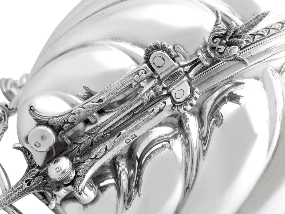 An antique Victorian sterling silver folding biscuit box featuring shell-form compartments, an ornate looped handle, and an engraved 1897 monogram. View X