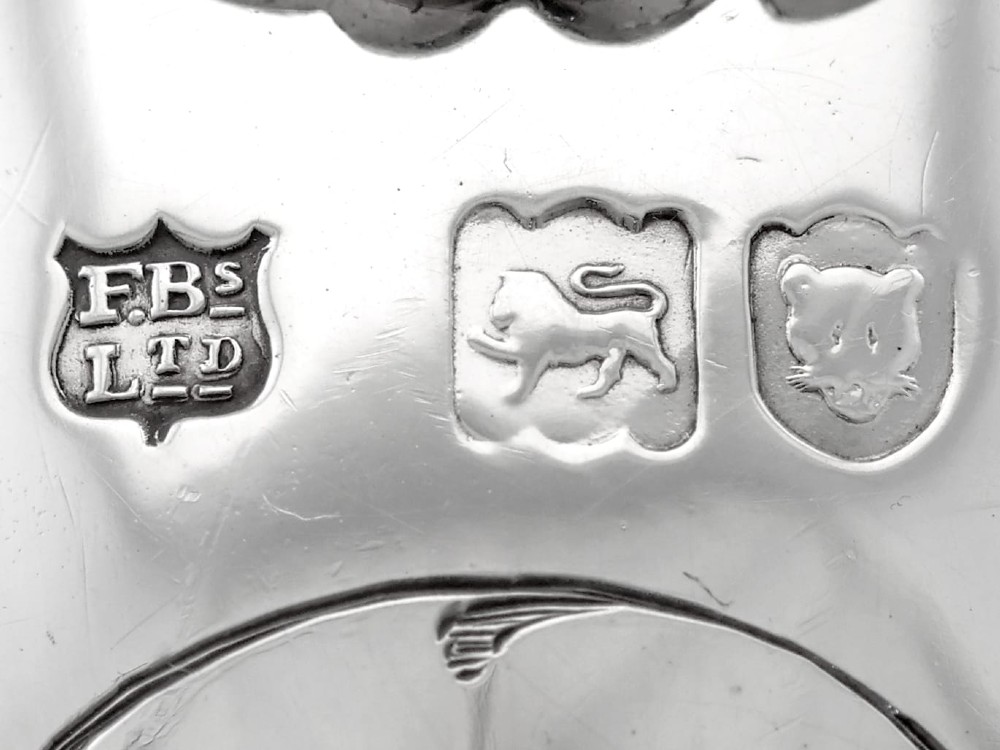An antique Victorian sterling silver folding biscuit box featuring shell-form compartments, an ornate looped handle, and an engraved 1897 monogram. View XIII