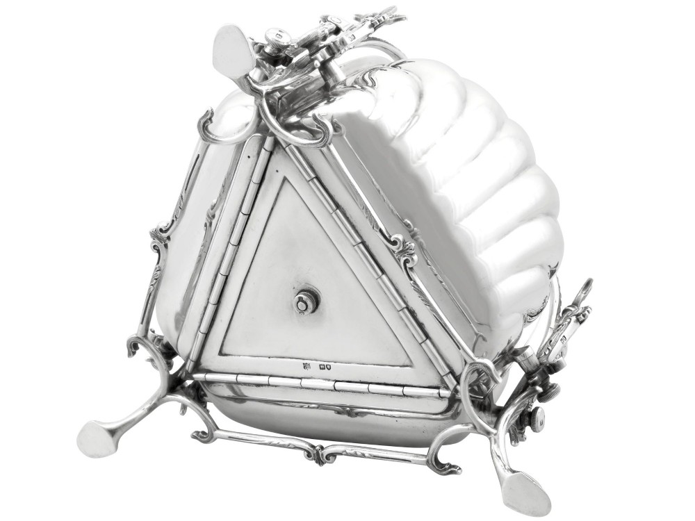 An antique Victorian sterling silver folding biscuit box featuring shell-form compartments, an ornate looped handle, and an engraved 1897 monogram. View XIV