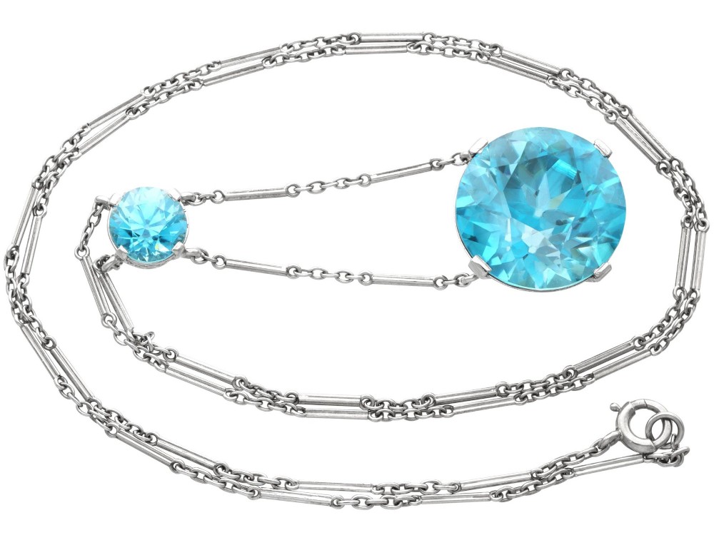 An Art Deco 18ct white gold drop pendant set with two round brilliant-cut bright blue zircon gemstones suspended on delicate bar links. View VII