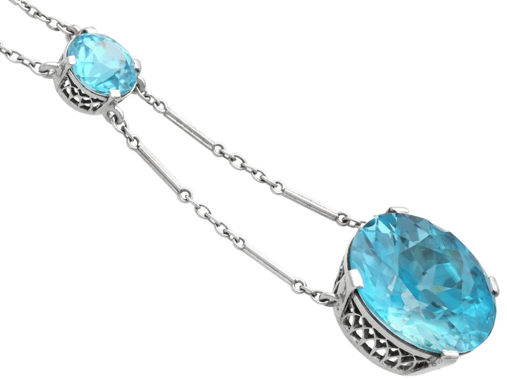 An Art Deco 18ct white gold drop pendant set with two round brilliant-cut bright blue zircon gemstones suspended on delicate bar links. View VIII