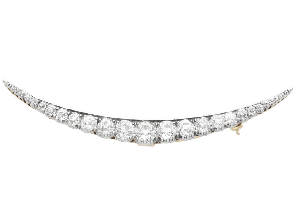An antique crescent-shaped brooch set with a row of graduated diamonds mounted in gold and silver.