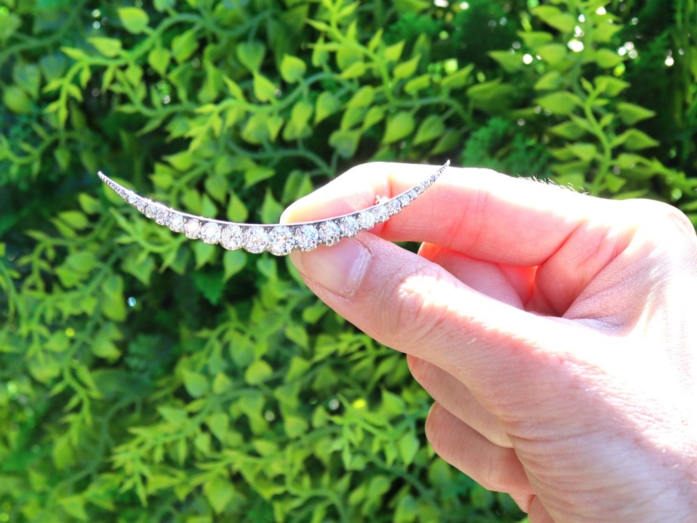 An antique crescent-shaped brooch set with a row of graduated diamonds mounted in gold and silver. View II