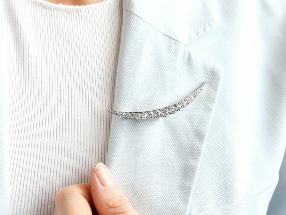 An antique crescent-shaped brooch set with a row of graduated diamonds mounted in gold and silver. View IV