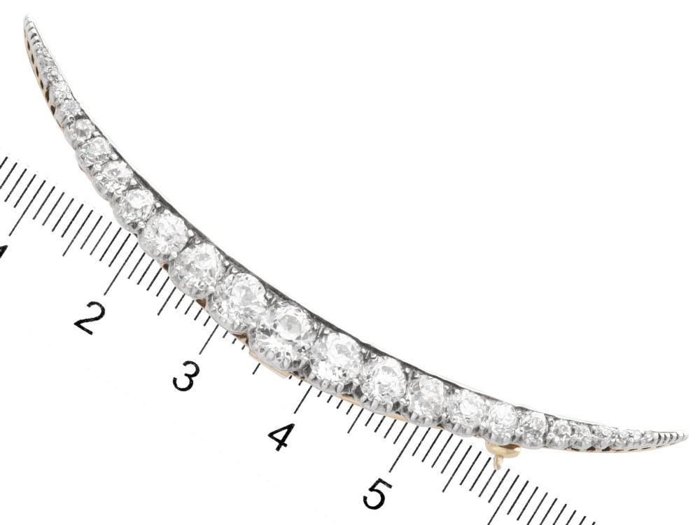 An antique crescent-shaped brooch set with a row of graduated diamonds mounted in gold and silver. View XI