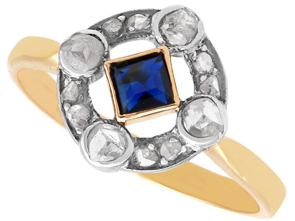 An 18ct yellow gold ring featuring a central square blue sapphire surrounded by an openwork diamond-set frame.