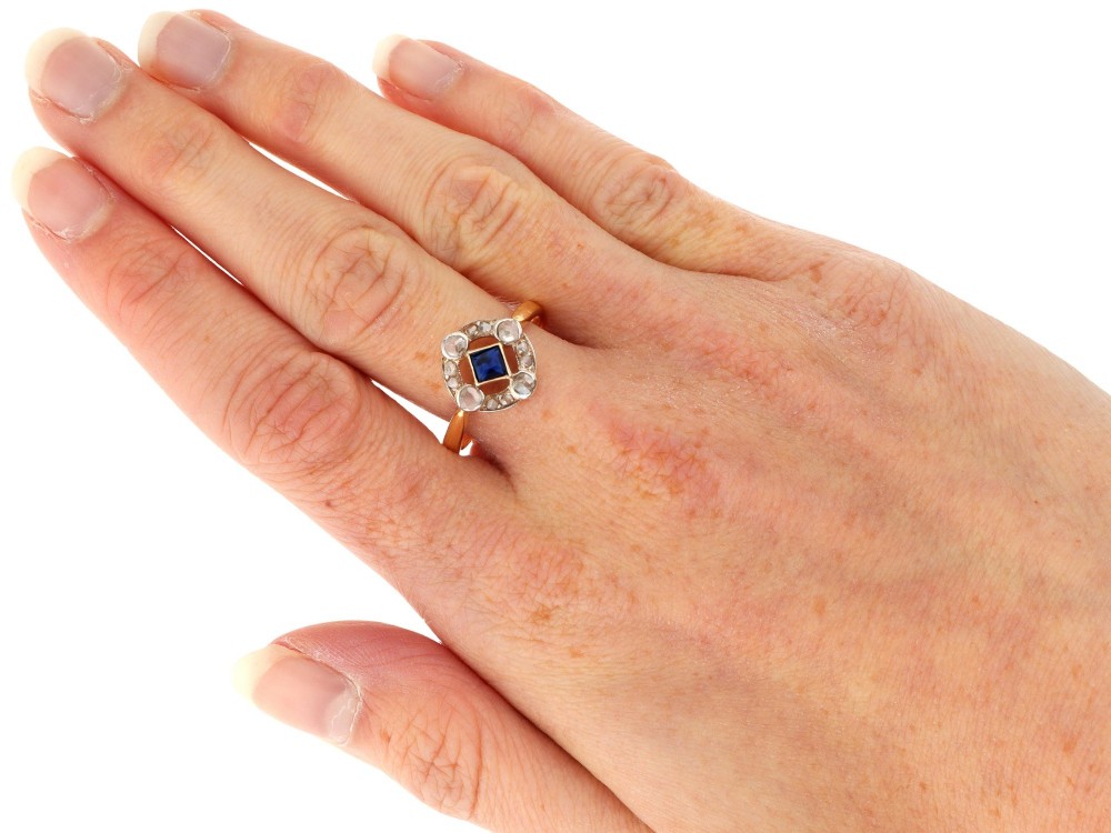 An 18ct yellow gold ring featuring a central square blue sapphire surrounded by an openwork diamond-set frame. View IX