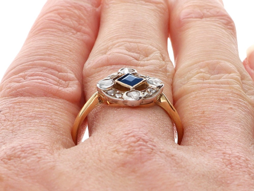 An 18ct yellow gold ring featuring a central square blue sapphire surrounded by an openwork diamond-set frame. View XI