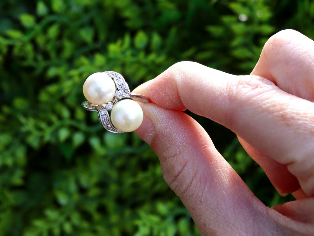 A circa 1950 white gold crossover cocktail ring featuring two cultured pearls flanked by diamond-accented bypass shoulders. View II