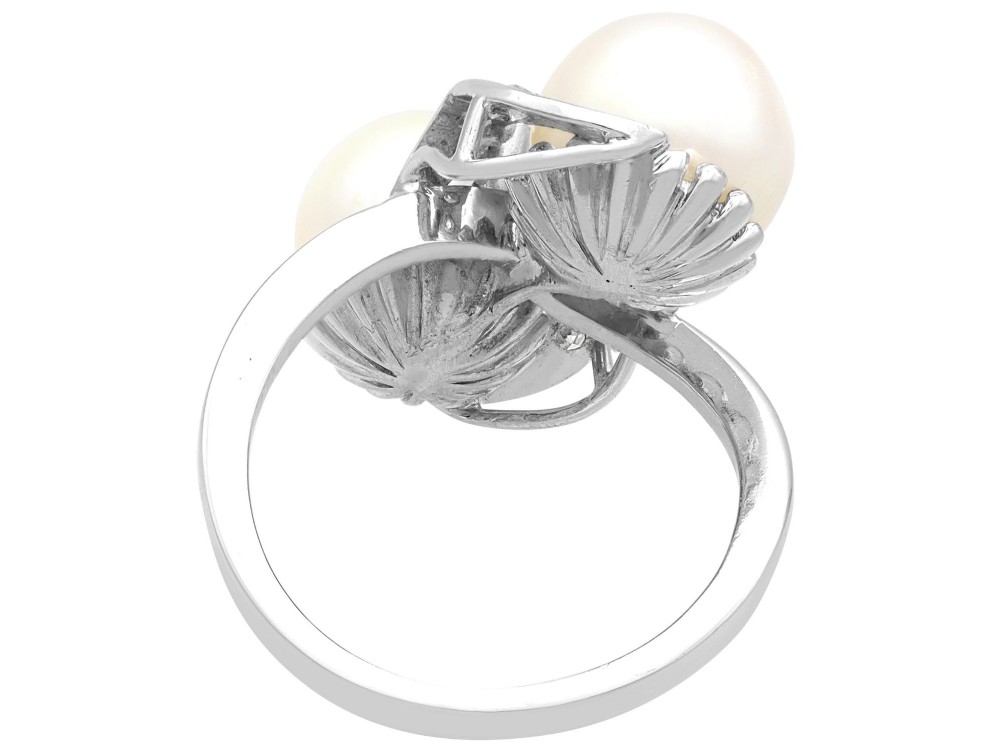 A circa 1950 white gold crossover cocktail ring featuring two cultured pearls flanked by diamond-accented bypass shoulders. View VIII