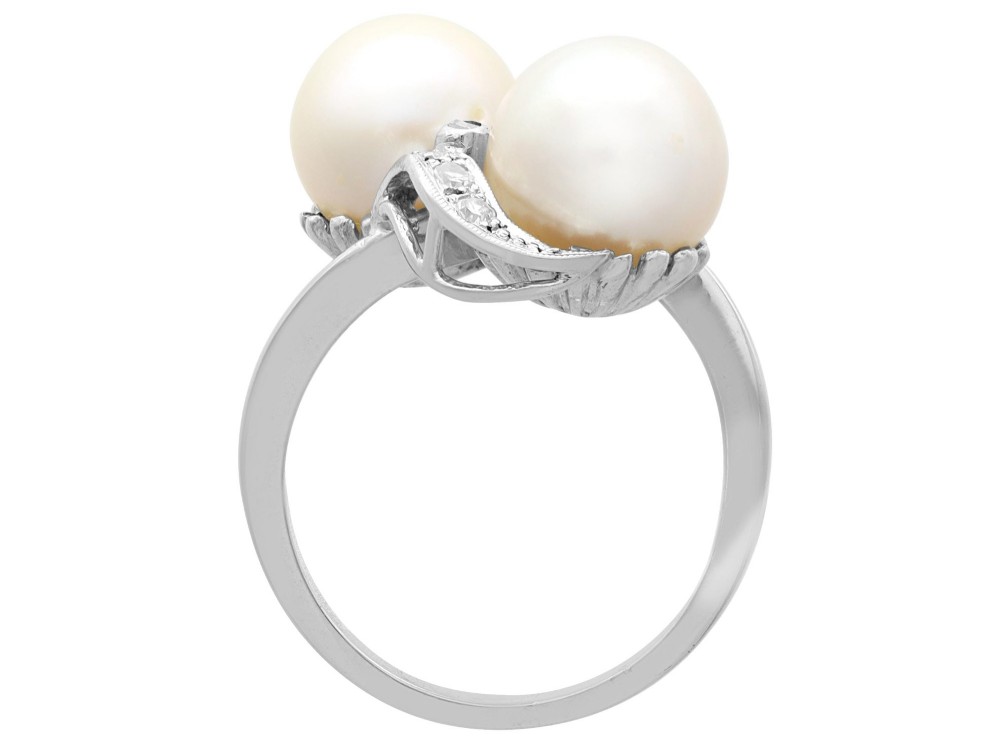 A circa 1950 white gold crossover cocktail ring featuring two cultured pearls flanked by diamond-accented bypass shoulders. View IX