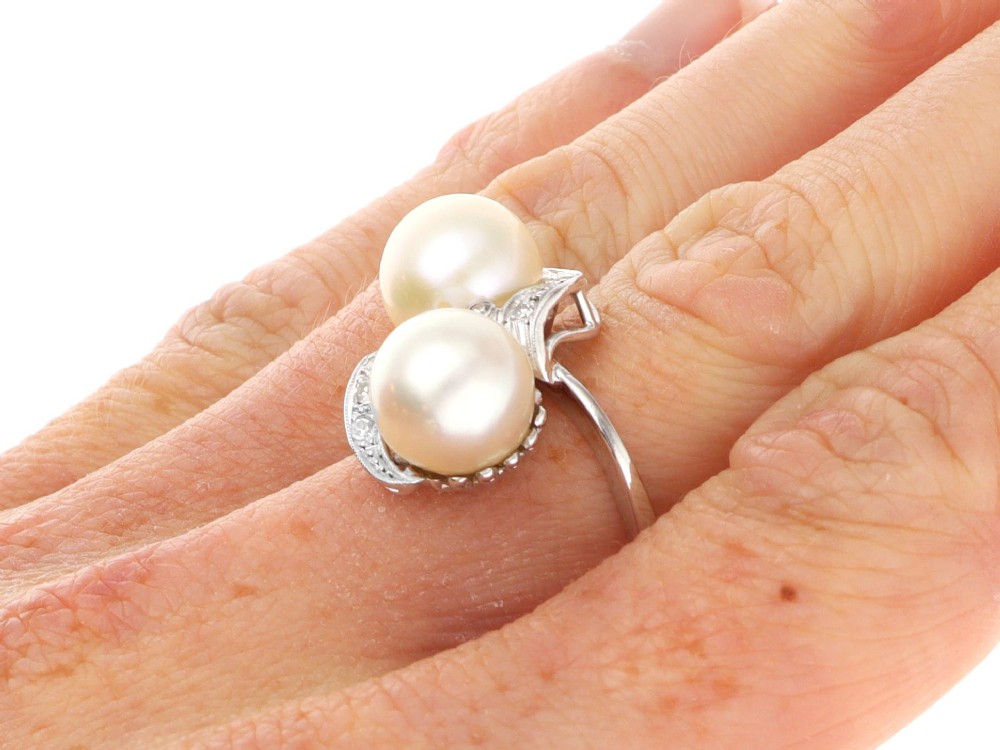 A circa 1950 white gold crossover cocktail ring featuring two cultured pearls flanked by diamond-accented bypass shoulders. View XII