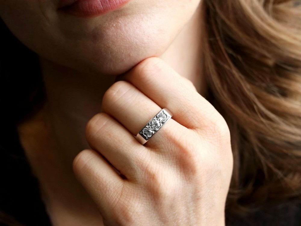 An 18ct white gold Art Deco trilogy ring featuring three round diamonds set horizontally across a wide band. View III
