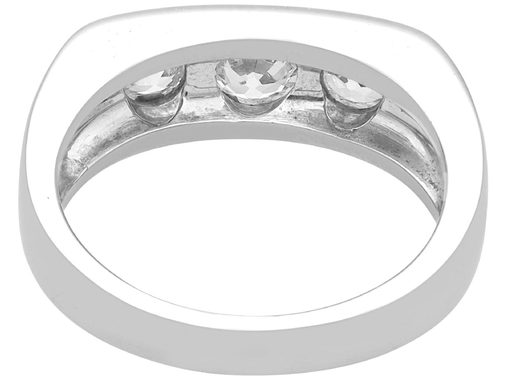 An 18ct white gold Art Deco trilogy ring featuring three round diamonds set horizontally across a wide band. View VI