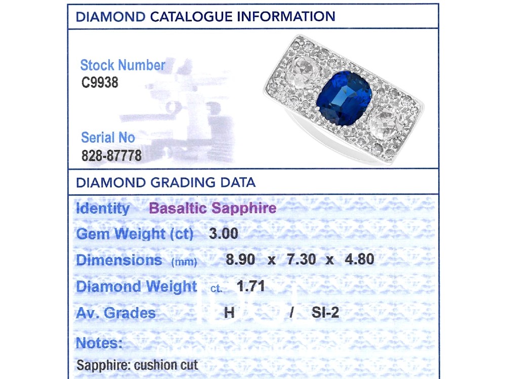 An Art Deco platinum plaque ring set with a central blue sapphire flanked by two large diamonds and surrounded by smaller pave-set diamonds. View XI