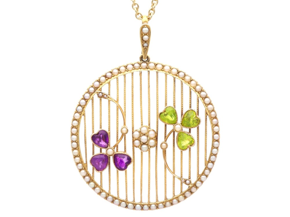 A circular 18ct yellow gold openwork pendant set with seed pearls along the outer rim, containing peridot and amethyst trefoil motifs and a central seed pearl cluster.