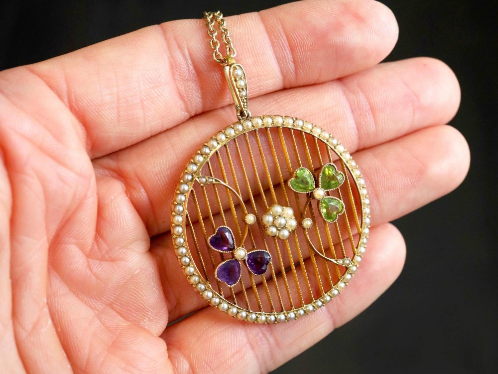 A circular 18ct yellow gold openwork pendant set with seed pearls along the outer rim, containing peridot and amethyst trefoil motifs and a central seed pearl cluster. View III