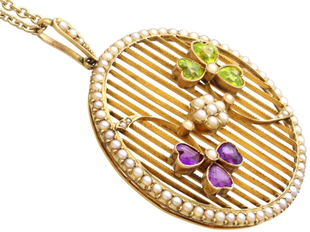 A circular 18ct yellow gold openwork pendant set with seed pearls along the outer rim, containing peridot and amethyst trefoil motifs and a central seed pearl cluster. View IX