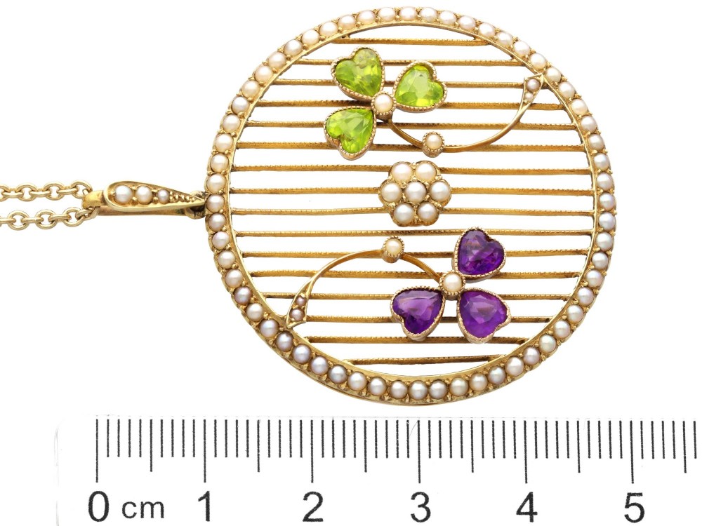 A circular 18ct yellow gold openwork pendant set with seed pearls along the outer rim, containing peridot and amethyst trefoil motifs and a central seed pearl cluster. View XI