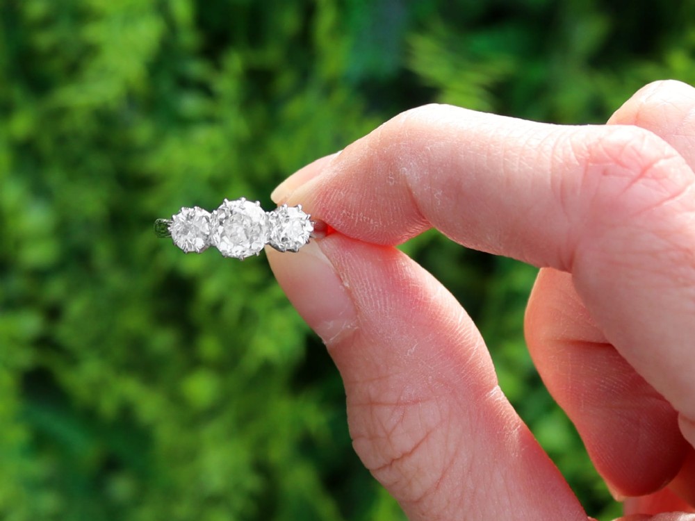 An Art Deco platinum ring set with three claw-set round diamonds positioned horizontally along the band. View II