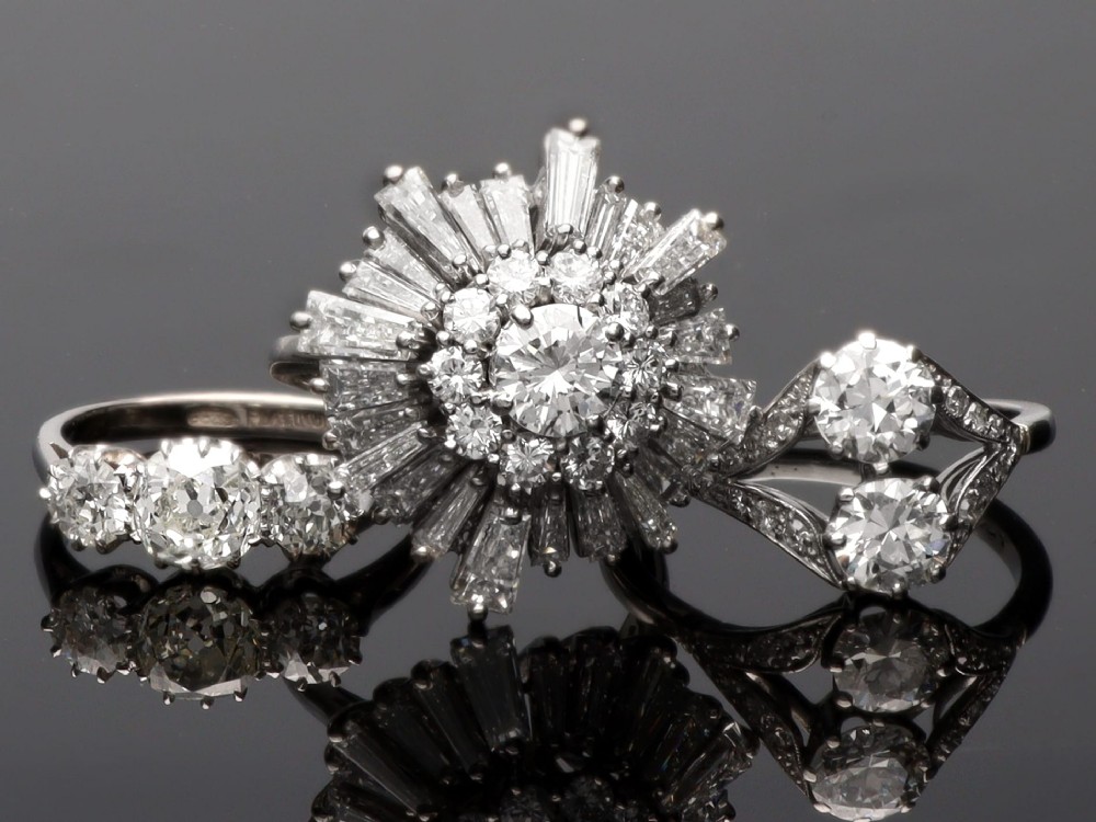 An Art Deco platinum ring set with three claw-set round diamonds positioned horizontally along the band. View V