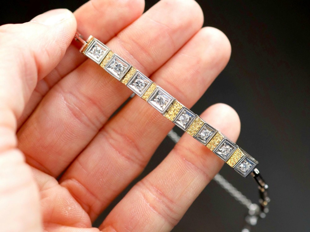 An Art Deco two-tone 18ct gold and white metal link bracelet featuring square diamond-set panels alternating with textured gold links. View IV