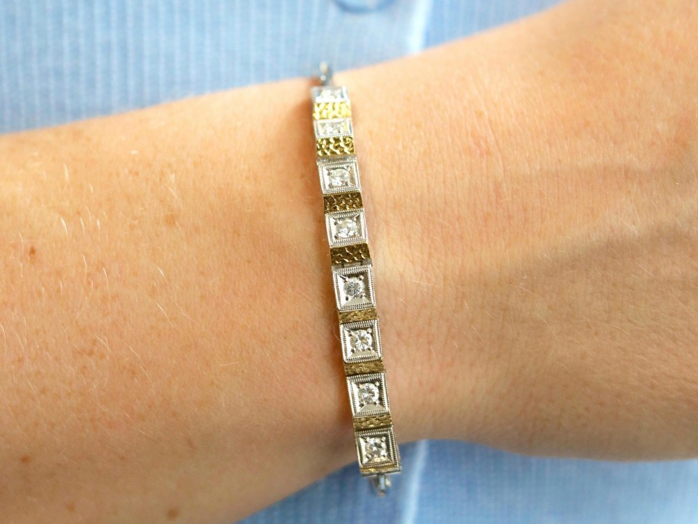 An Art Deco two-tone 18ct gold and white metal link bracelet featuring square diamond-set panels alternating with textured gold links. View V