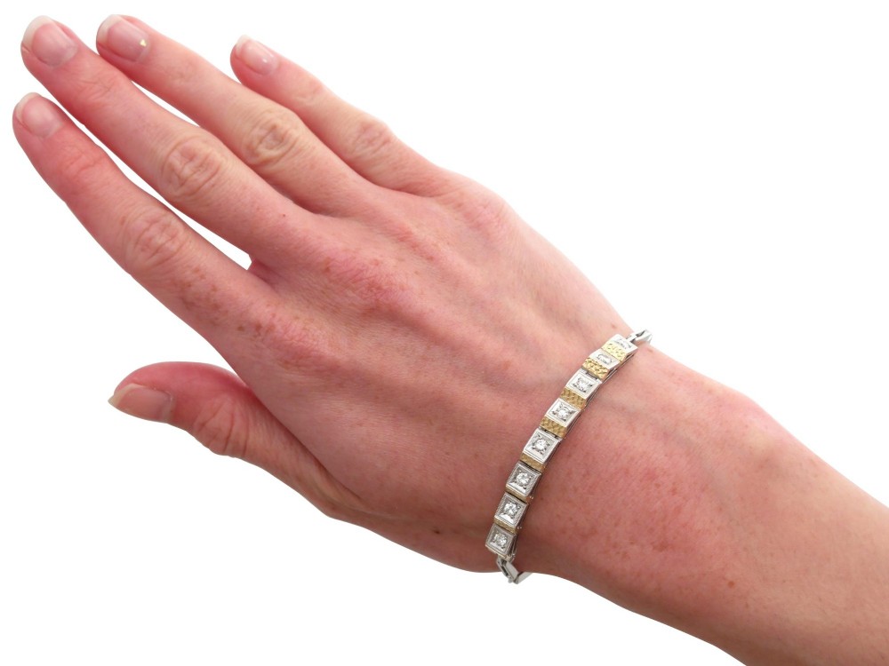 An Art Deco two-tone 18ct gold and white metal link bracelet featuring square diamond-set panels alternating with textured gold links. View XII