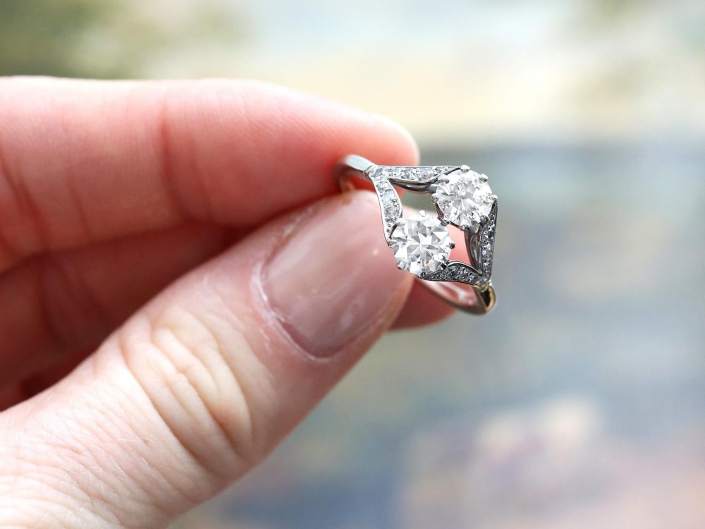 An Art Deco platinum two stone ring featuring round diamonds arranged vertically within a crossover frame with diamond-set shoulders. View III