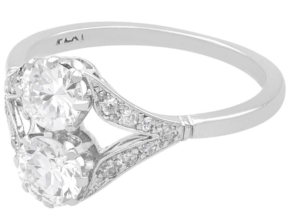 An Art Deco platinum two stone ring featuring round diamonds arranged vertically within a crossover frame with diamond-set shoulders. View VII