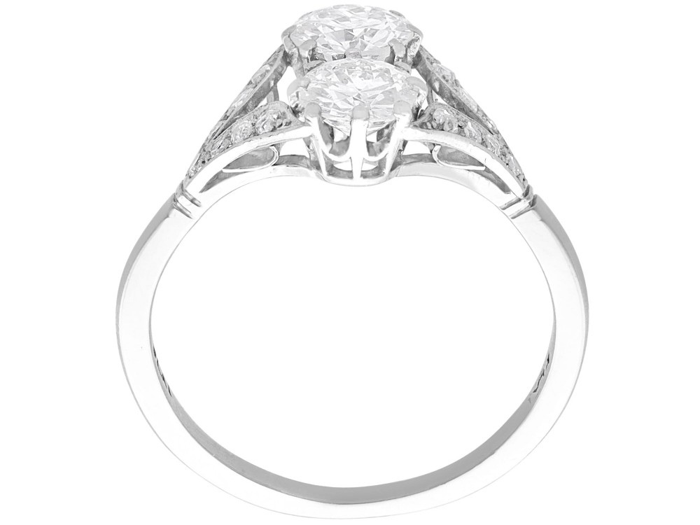 An Art Deco platinum two stone ring featuring round diamonds arranged vertically within a crossover frame with diamond-set shoulders. View IX