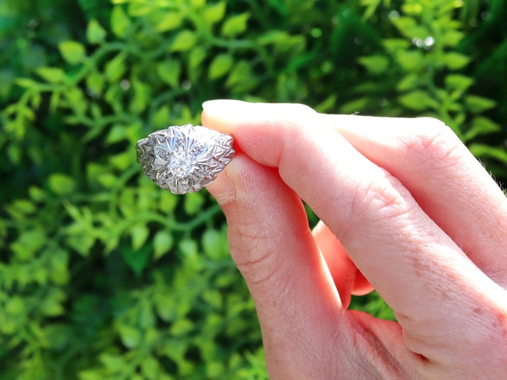 An Art Deco 18ct white gold dress ring with engraved floral textured petals and a central diamond accent. View II