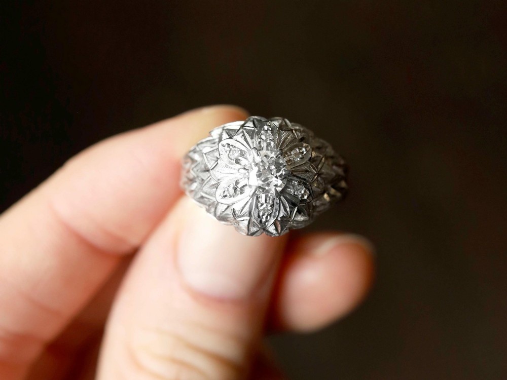 An Art Deco 18ct white gold dress ring with engraved floral textured petals and a central diamond accent. View III