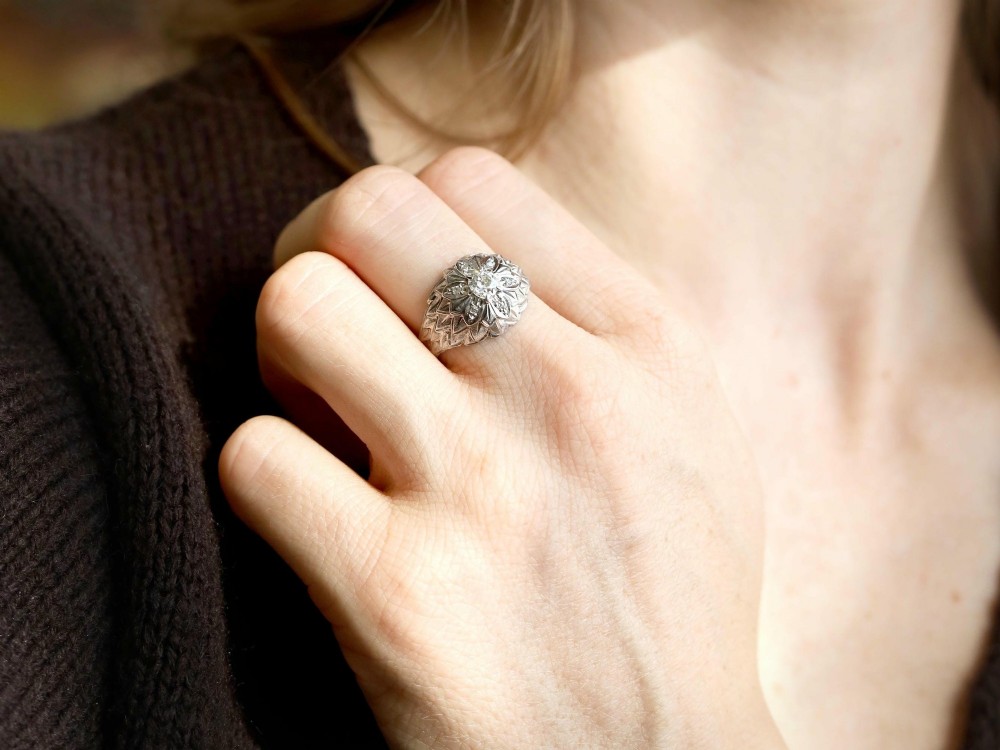 An Art Deco 18ct white gold dress ring with engraved floral textured petals and a central diamond accent. View IV