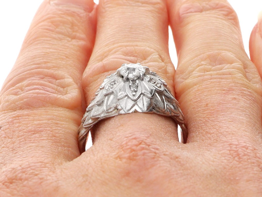 An Art Deco 18ct white gold dress ring with engraved floral textured petals and a central diamond accent. View XII